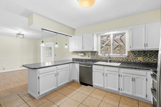 kitchen featuring a peninsula, white cabinetry, appliances with stainless steel finishes, and a sink