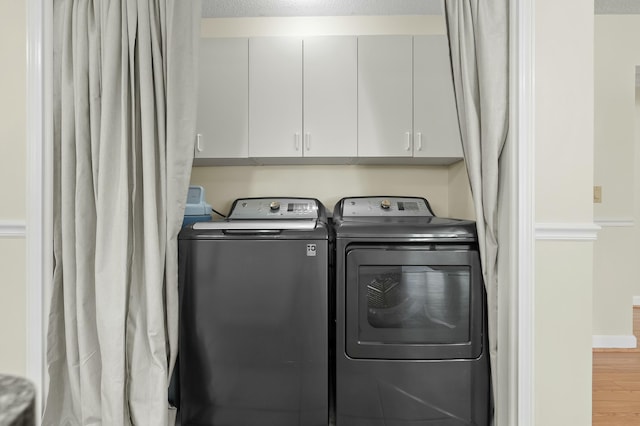 clothes washing area with a textured ceiling, washing machine and clothes dryer, and wood finished floors