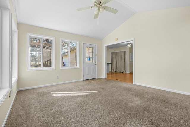 carpeted empty room featuring baseboards, vaulted ceiling, and a ceiling fan