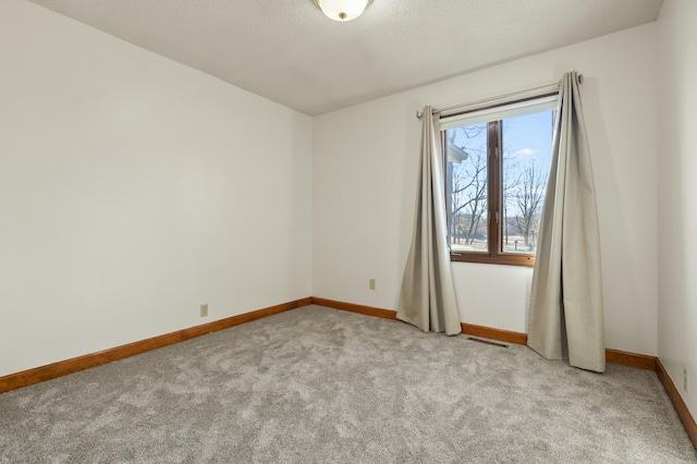 unfurnished room with light carpet, a textured ceiling, visible vents, and baseboards