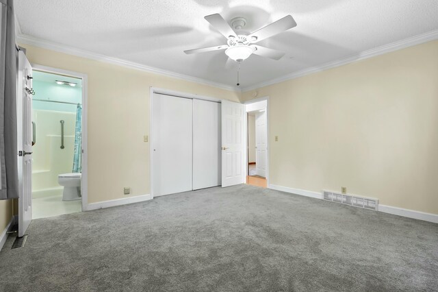 unfurnished bedroom featuring ornamental molding, a closet, visible vents, and carpet floors