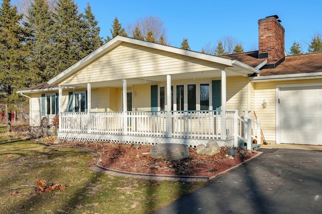 view of front of home with a garage, covered porch, and a chimney