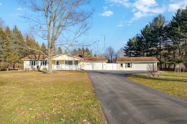 ranch-style house with a detached garage, fence, a porch, and a front yard