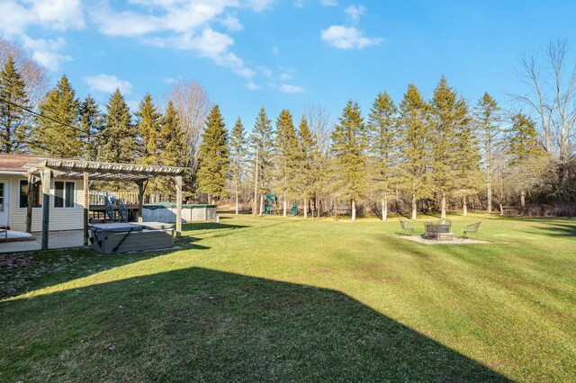 view of yard featuring a hot tub, a fire pit, a patio, a pool, and a pergola