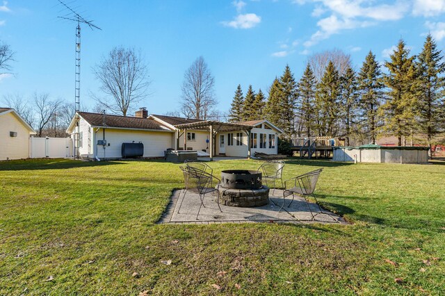 back of property with a fire pit, fence, a lawn, and a patio