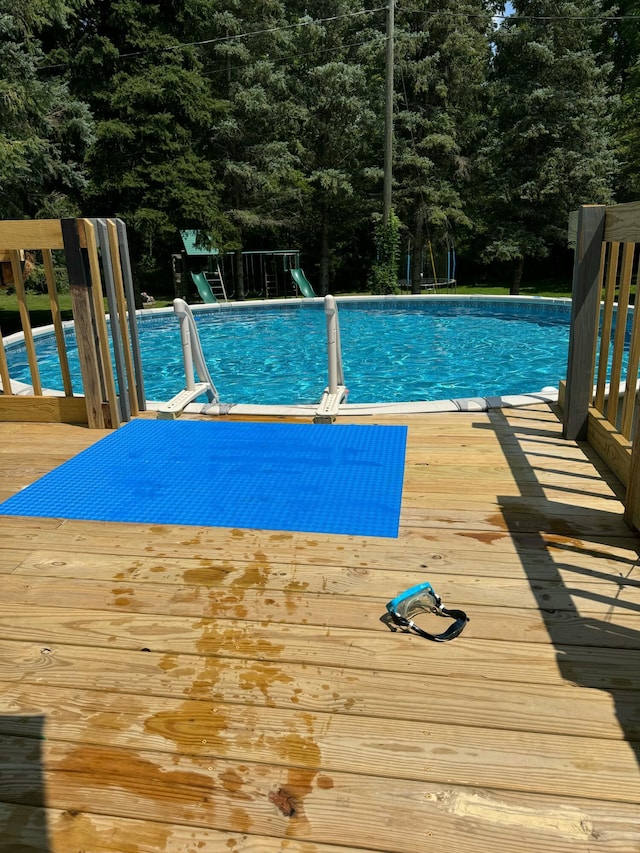 outdoor pool featuring playground community and a deck