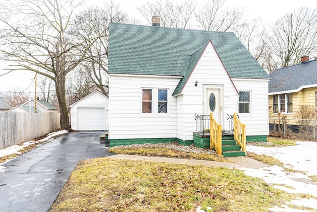 view of front of house with a garage, a shingled roof, a chimney, an outbuilding, and fence