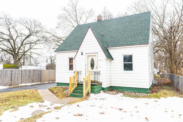 view of front of property with a shingled roof, a chimney, and fence private yard