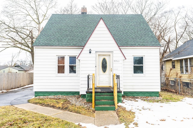 view of front of house with a shingled roof, fence, and a chimney