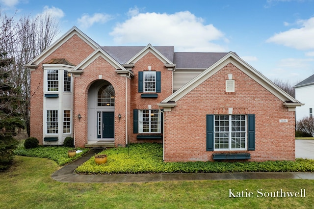 traditional-style house featuring brick siding and a front yard