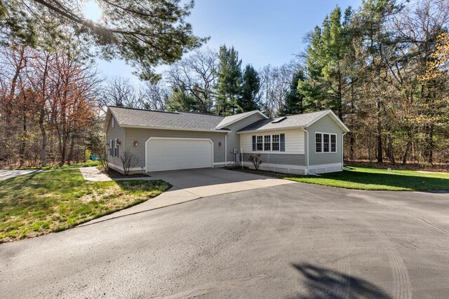 ranch-style home with a garage, roof with shingles, concrete driveway, and a front lawn