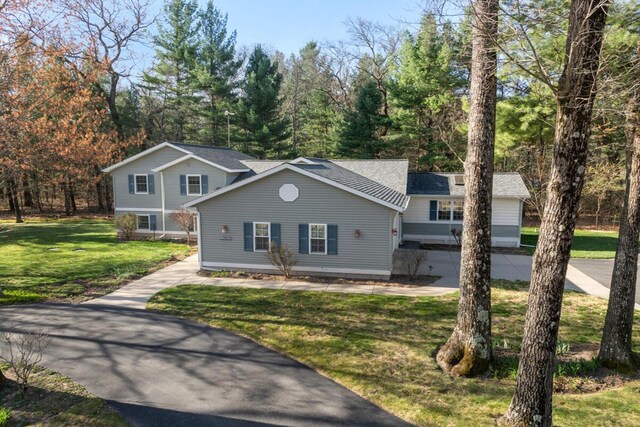 view of front of house featuring roof with shingles and a front yard