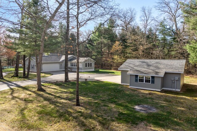 view of yard featuring a garage, an outbuilding, and driveway