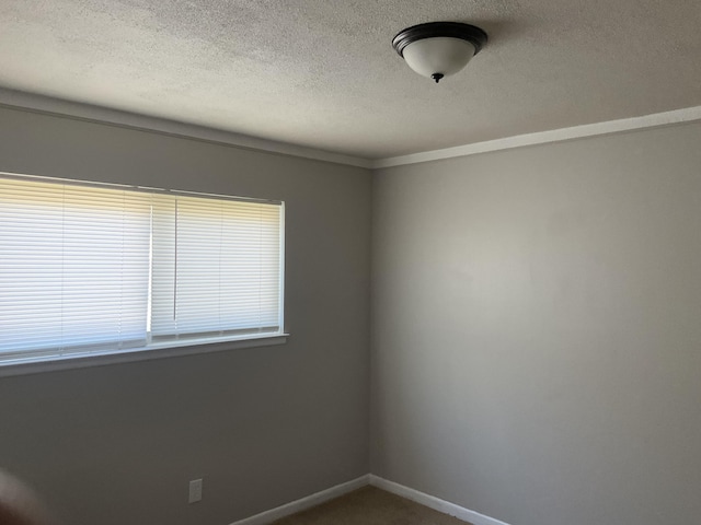 unfurnished room with baseboards and a textured ceiling