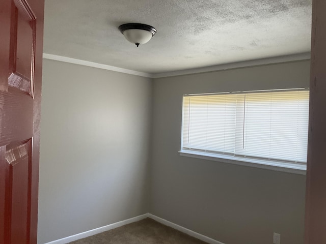 empty room with dark carpet, a textured ceiling, and baseboards