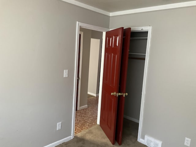 unfurnished bedroom with a closet, carpet, visible vents, and baseboards