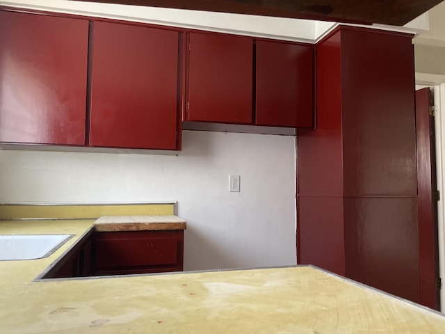 kitchen featuring red cabinetry and light countertops