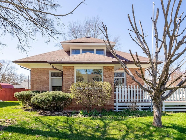 view of front facade featuring a front yard, brick siding, and fence