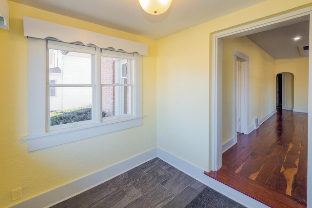 hall featuring arched walkways, visible vents, and baseboards