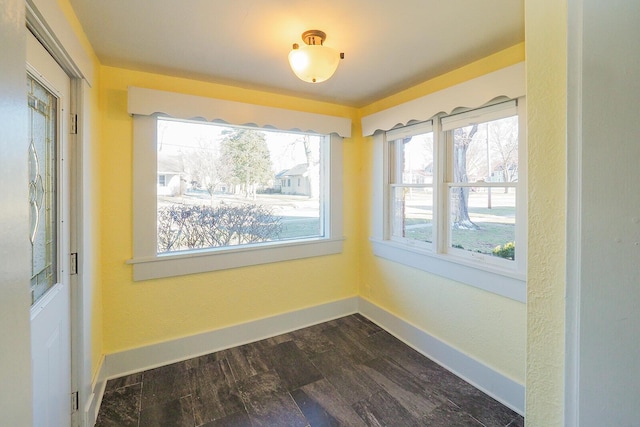 empty room with dark wood-type flooring and baseboards