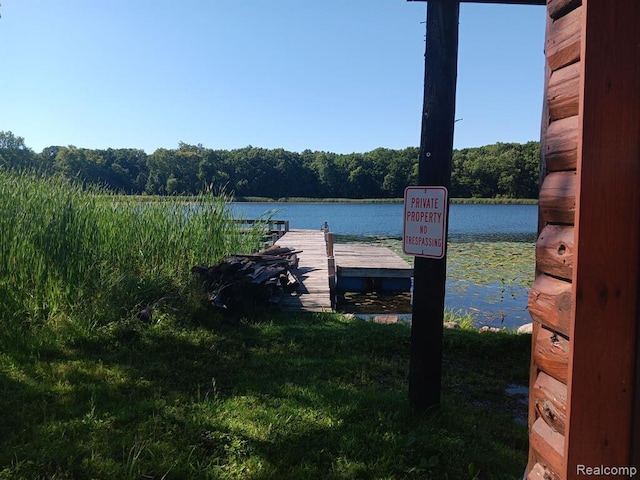 view of dock with a water view and a wooded view