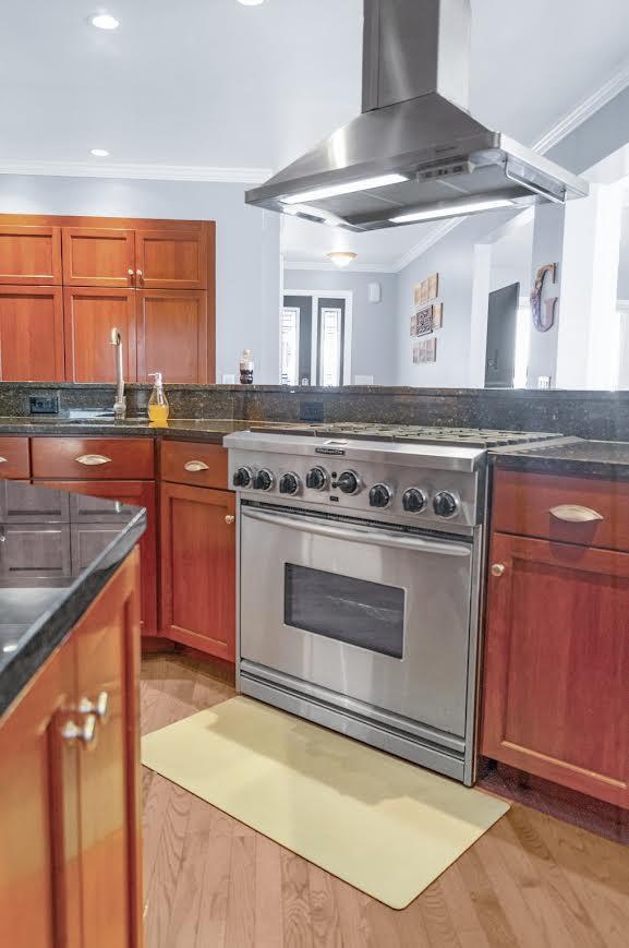 5007 S 42nd St, Climax, MI 49034 - kitchen with exhaust hood, stainless steel stove, ornamental molding, a sink, and brown cabinetry