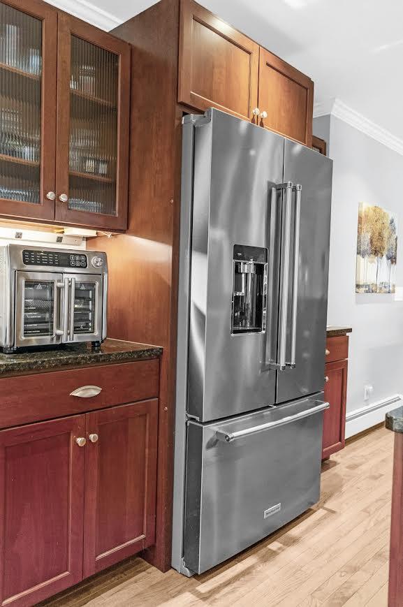 5007 S 42nd St, Climax, MI 49034 - kitchen with high quality fridge, a baseboard radiator, ornamental molding, light wood-type flooring, and dark stone counters