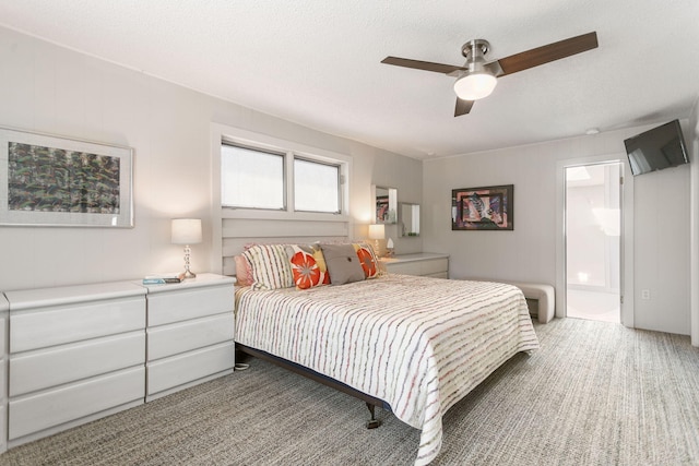 bedroom with a ceiling fan, connected bathroom, light colored carpet, and a textured ceiling