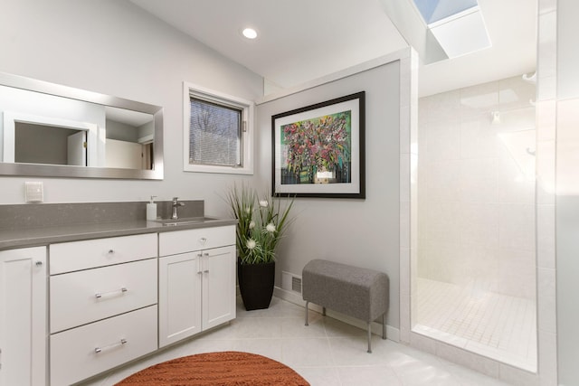 bathroom featuring vanity, tile patterned floors, baseboards, and tiled shower