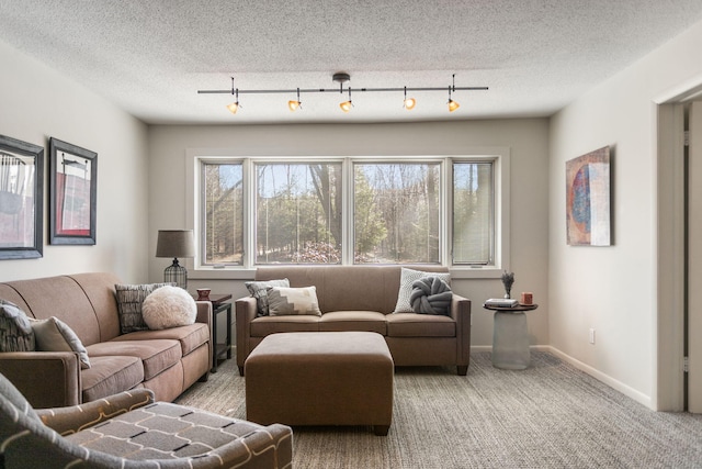 carpeted living room featuring track lighting, baseboards, and a textured ceiling