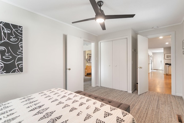 bedroom featuring a ceiling fan, carpet, baseboards, a closet, and crown molding