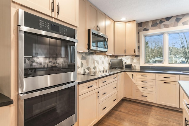 kitchen featuring stainless steel appliances, dark wood-type flooring, a textured ceiling, dark countertops, and tasteful backsplash