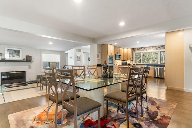 dining area featuring wood finished floors, recessed lighting, a fireplace, and visible vents