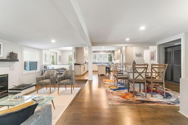 living room featuring a brick fireplace, recessed lighting, and wood finished floors