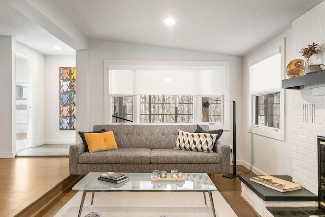 living area featuring vaulted ceiling, recessed lighting, a brick fireplace, and wood finished floors