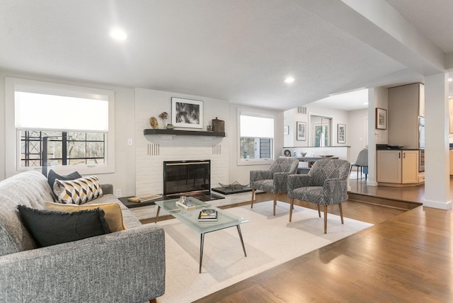 living area with a fireplace, plenty of natural light, wood finished floors, and recessed lighting