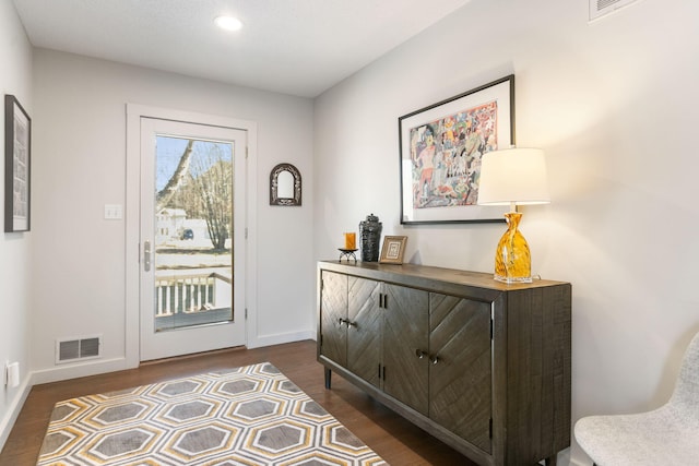 doorway to outside featuring a wealth of natural light, visible vents, baseboards, and dark wood-style flooring