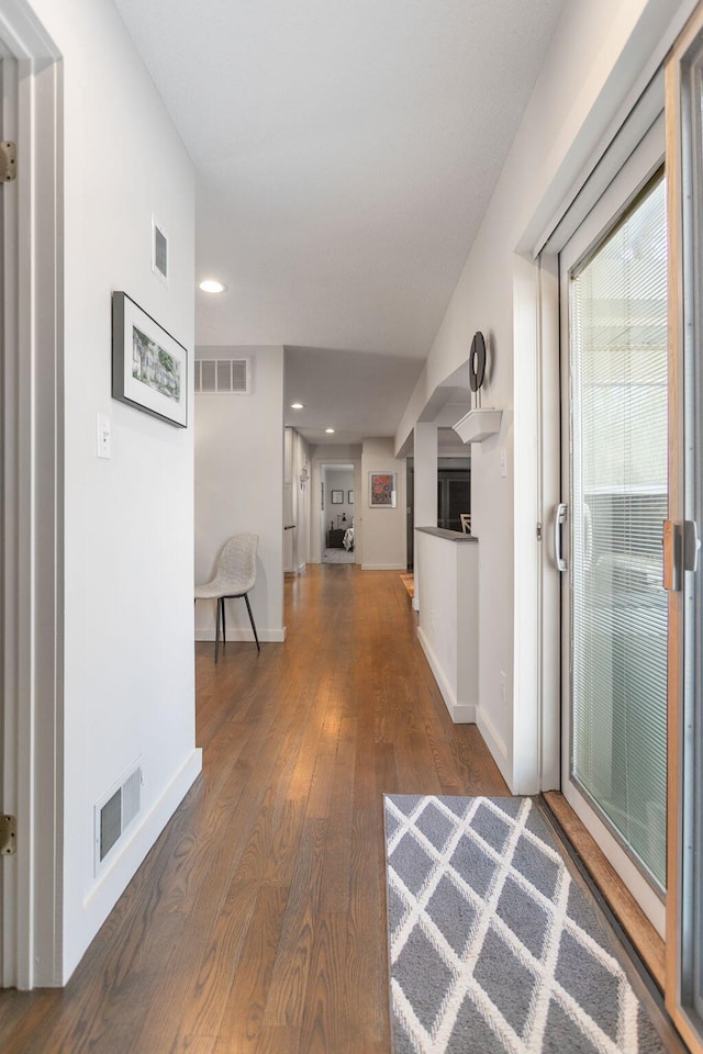 hall featuring visible vents, baseboards, and hardwood / wood-style floors