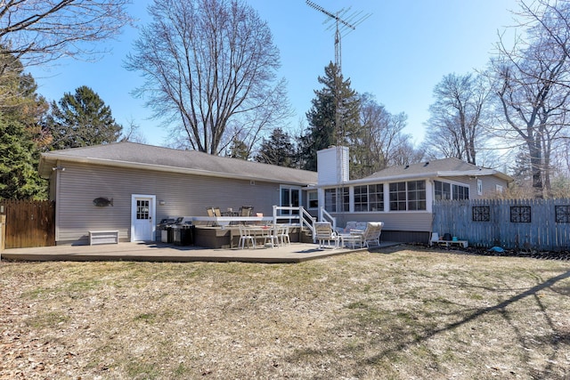 rear view of house with fence, a lawn, a sunroom, and a chimney