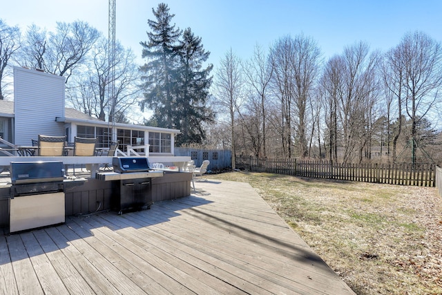 wooden deck featuring a yard, area for grilling, a fenced backyard, and a sunroom