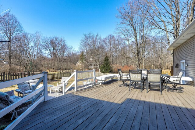 wooden deck with outdoor dining space and a fenced backyard