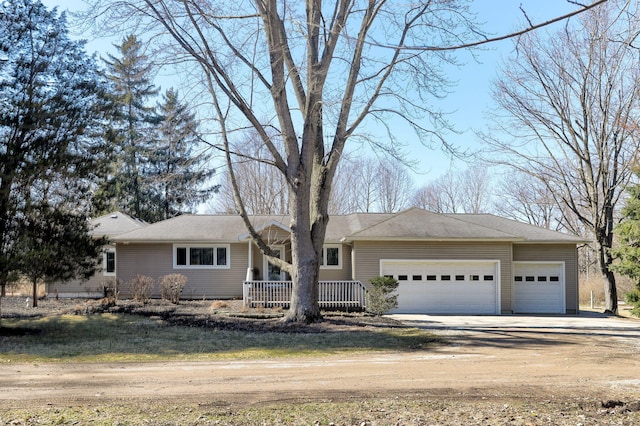 single story home with covered porch, a garage, and dirt driveway