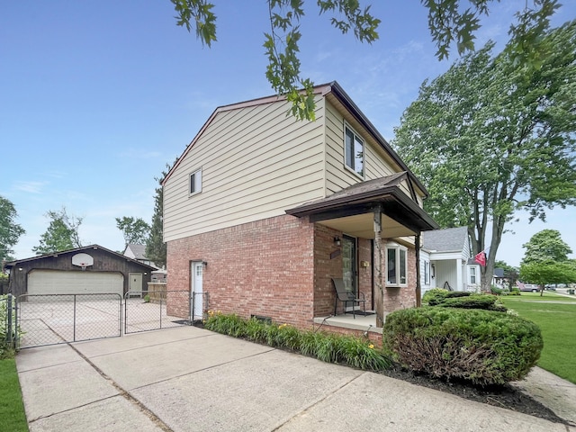 view of side of home with a garage, an outbuilding, a gate, fence, and brick siding