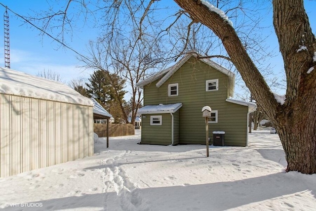 snow covered rear of property featuring an outdoor structure and central air condition unit