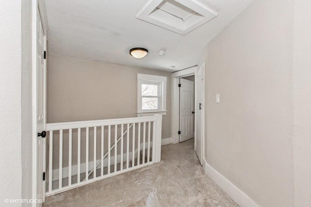 hallway featuring an upstairs landing, attic access, and baseboards