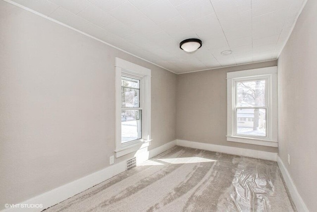 spare room featuring baseboards, visible vents, and light colored carpet