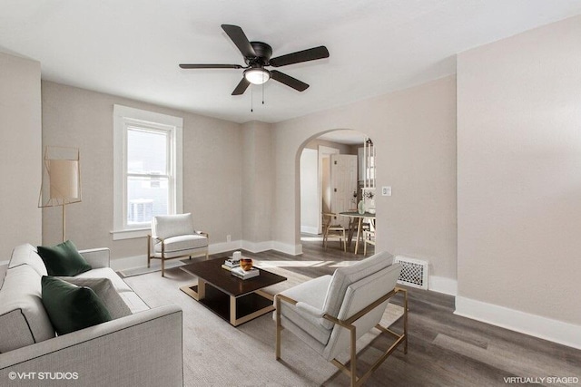 living area featuring arched walkways, visible vents, baseboards, and wood finished floors