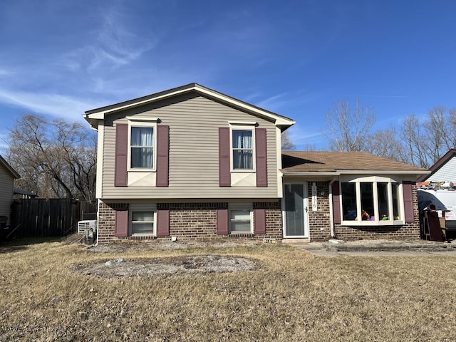 split level home featuring brick siding and fence