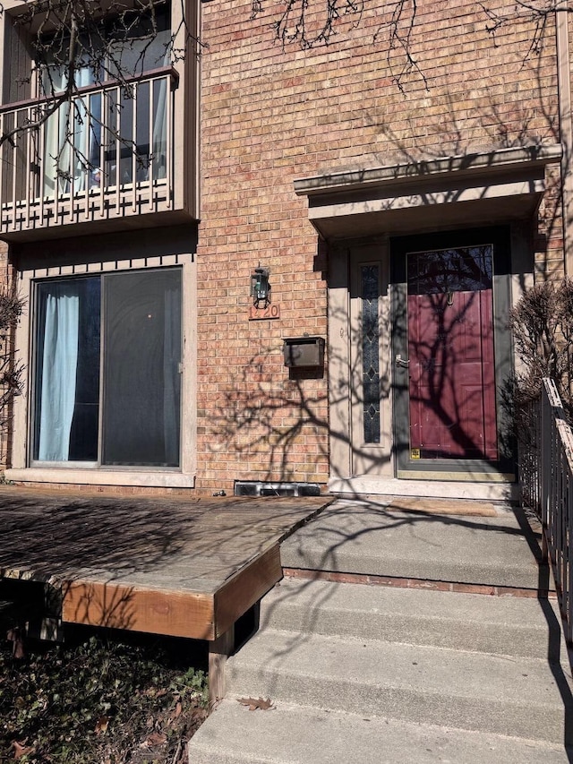 doorway to property with a balcony and brick siding