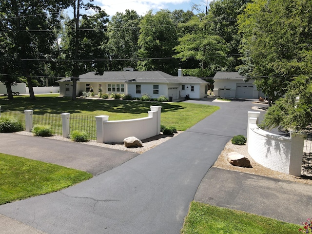 single story home with a garage, driveway, a fenced front yard, and a front yard